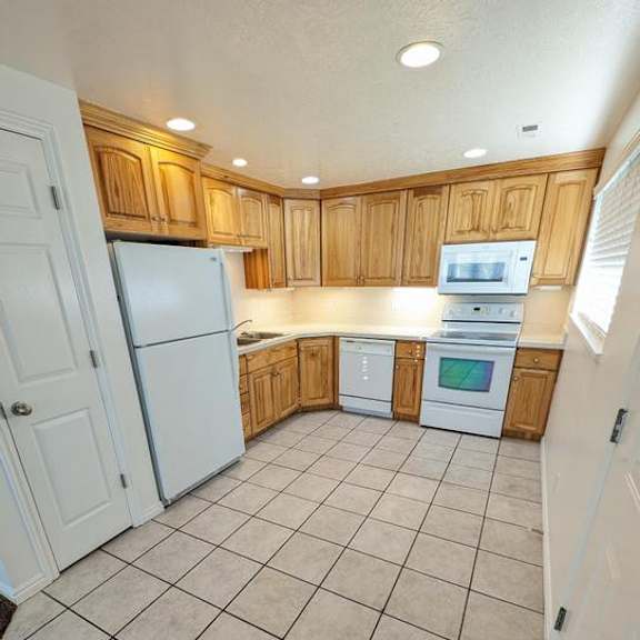 a kitchen with white appliances and wooden cabinets.