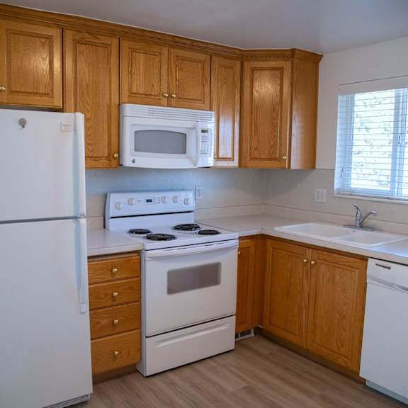 a kitchen with white appliances and wooden cabinets.