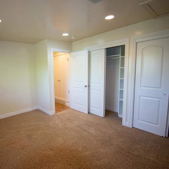 a room with white walls and carpeted floor with a doorway leading to another room.