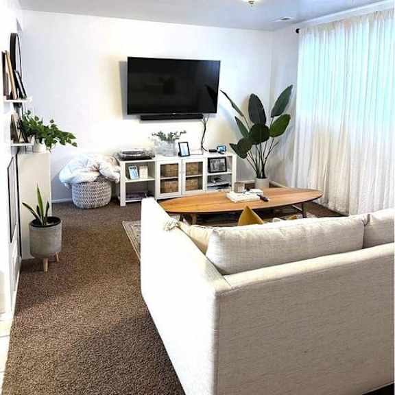 a living room with a white couch and a flat screen tv mounted on the wall.
