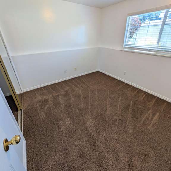 a room with a carpeted floor and a door on the left side.