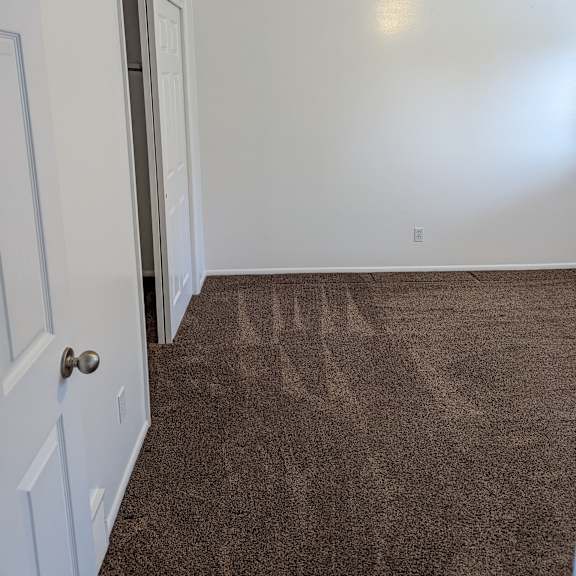 a room with a brown carpet and white walls.