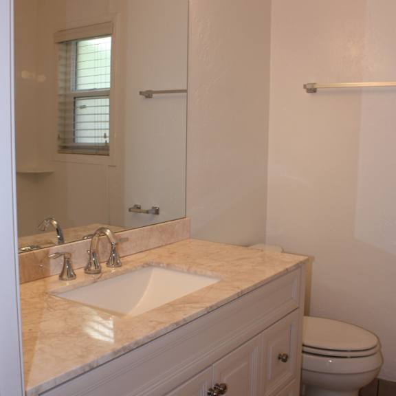 a white bathroom with a sink, toilet and mirror.