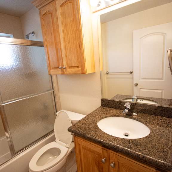 a bathroom with a toilet, sink, and wooden cabinets.