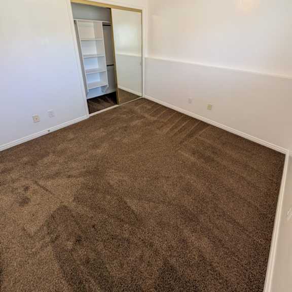 a room with a brown carpet and a white wall.