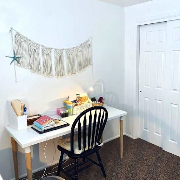 a white desk with a chair and a star decoration on the wall.