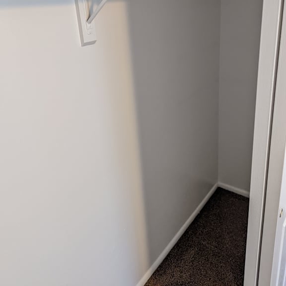a white closet with a rod hanging from the ceiling.