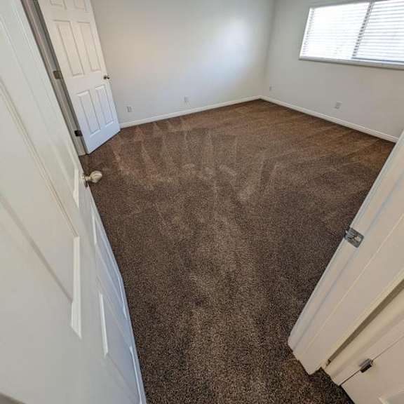 a room with a carpeted floor and a window with blinds.