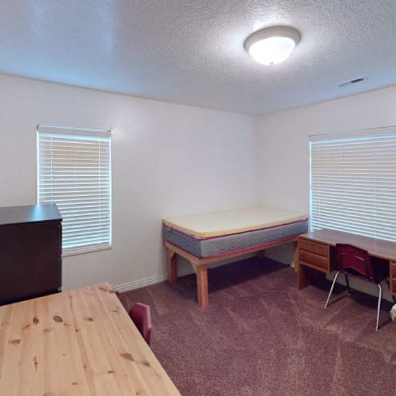 a room with a bed, a table, and a chair.