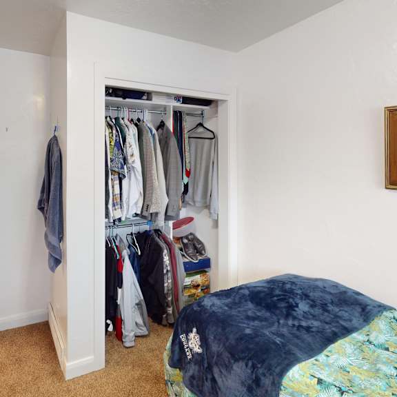 a bedroom with a bed, a wardrobe, and a painting on the wall.