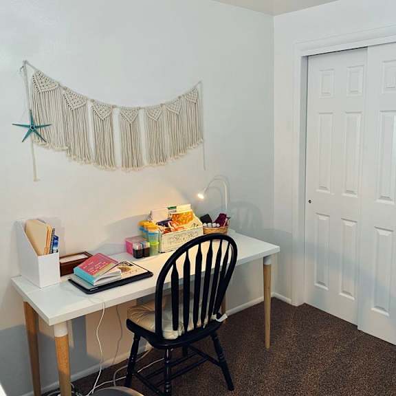 a white desk with a chair and a star decoration on the wall.