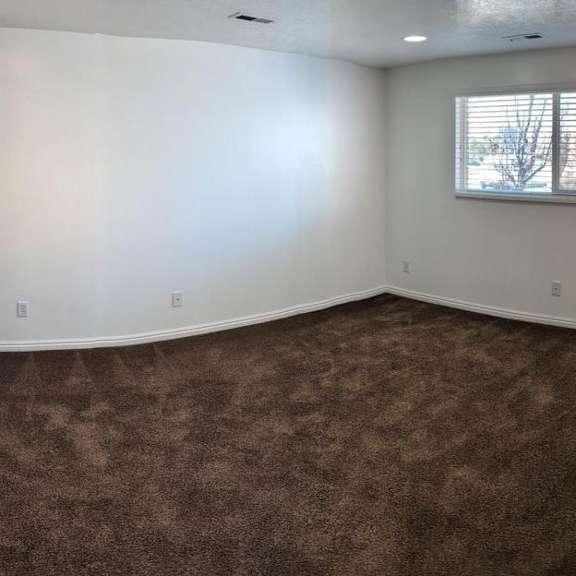 a room with a carpeted floor and a window with blinds.