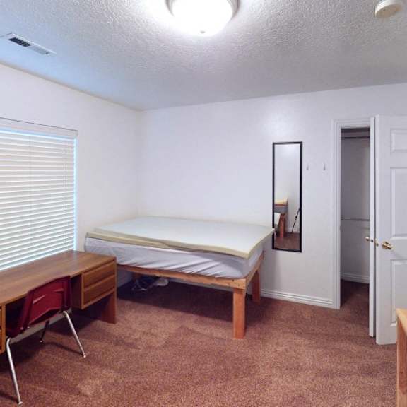 a bedroom with a bed, desk, and chair.