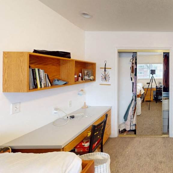 a bedroom with a bed, a desk, and a mirror.