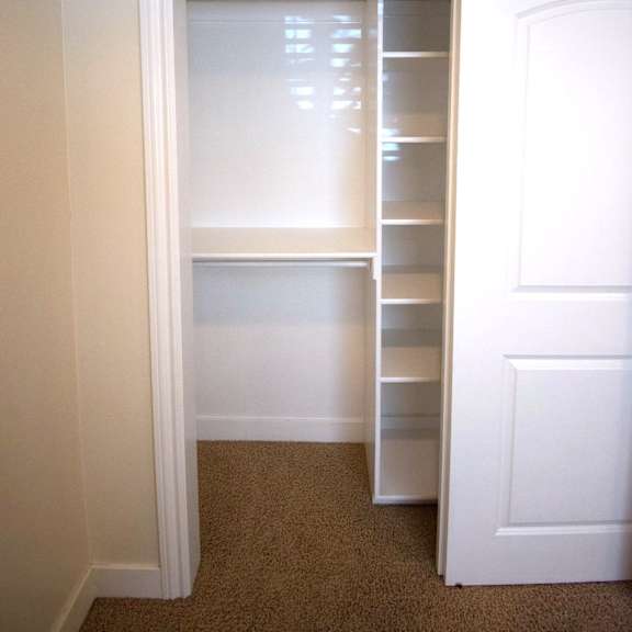 a white closet with shelves and a door.