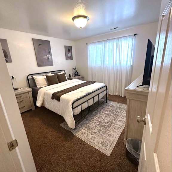 a bedroom with a bed, nightstand, and two pictures on the wall.