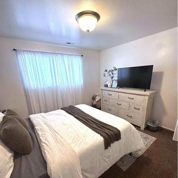a bedroom with a bed, a dresser, and a television.
