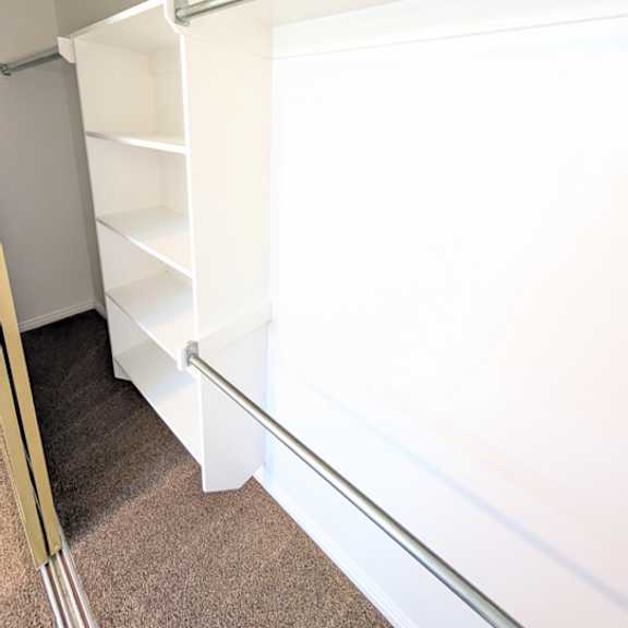a white shelving unit with four shelves is installed in a room.