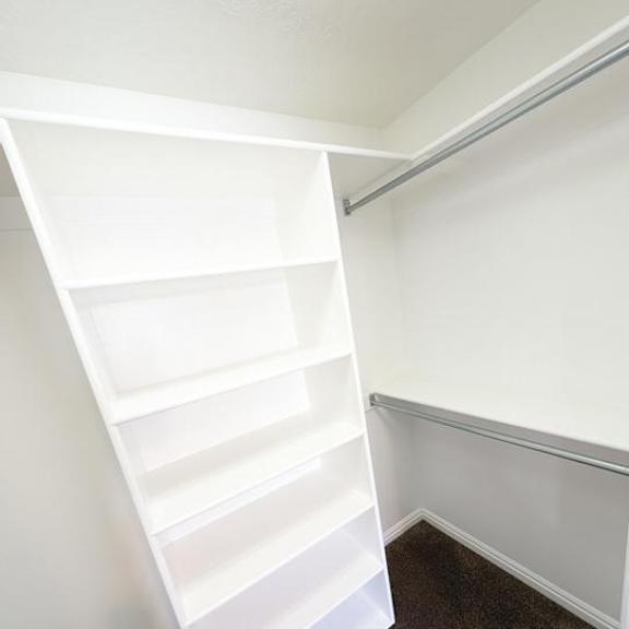 a white shelving unit in a corner of a room.
