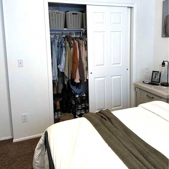a white bedroom with a bed, a wardrobe, and a nightstand.