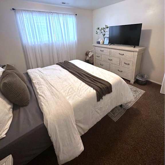 a bedroom with a bed, a dresser, and a television.