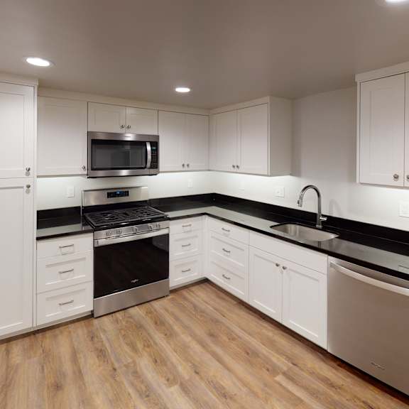 a modern kitchen with stainless steel appliances and white cabinets.