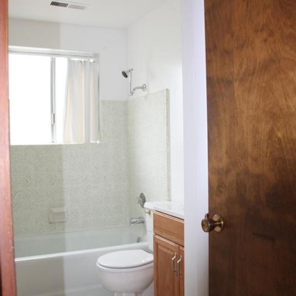 a white toilet sits in a bathroom next to a wooden door.