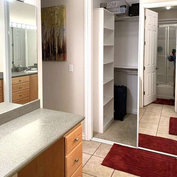 a white open closet with a black suitcase inside.