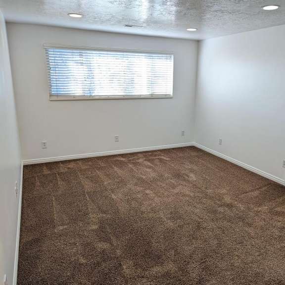 a room with a carpeted floor and a window with blinds.