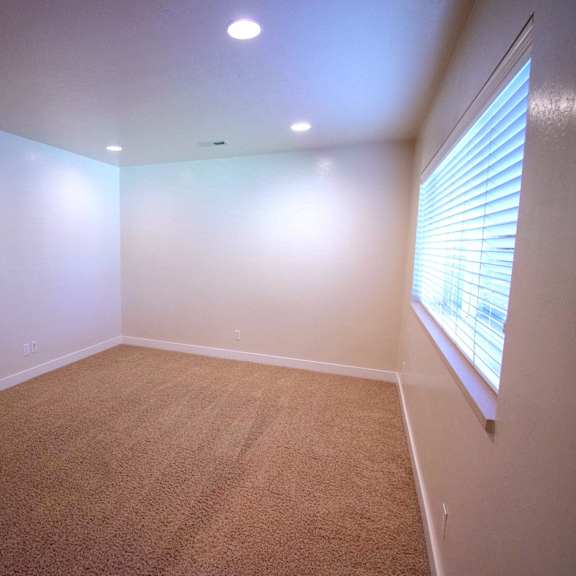 a room with carpeted floor and a window with blinds.