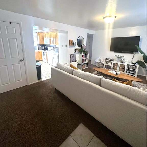 a living room with a white couch and a flat screen tv mounted on the wall.
