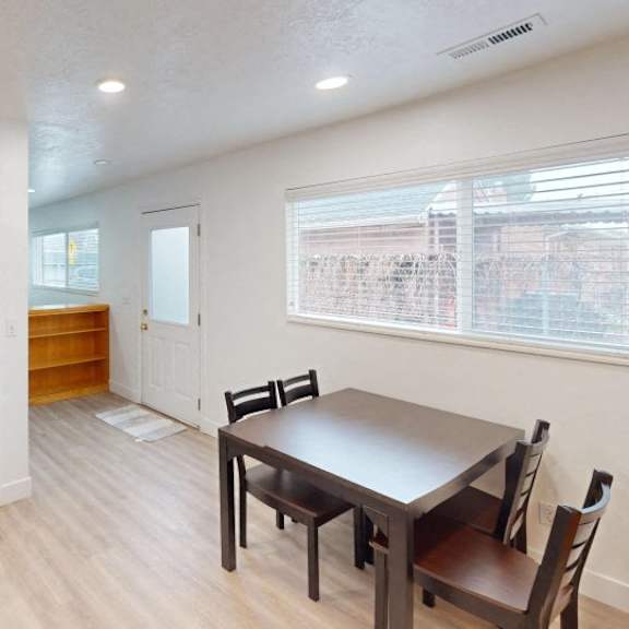 a kitchen with a refrigerator, table and chairs.