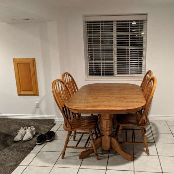 a wooden table and chairs are in a room with a window.
