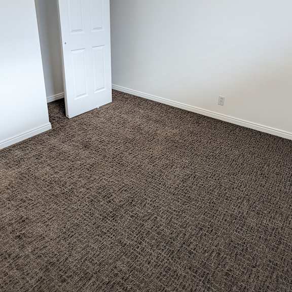 a room with a carpeted floor and a white door.