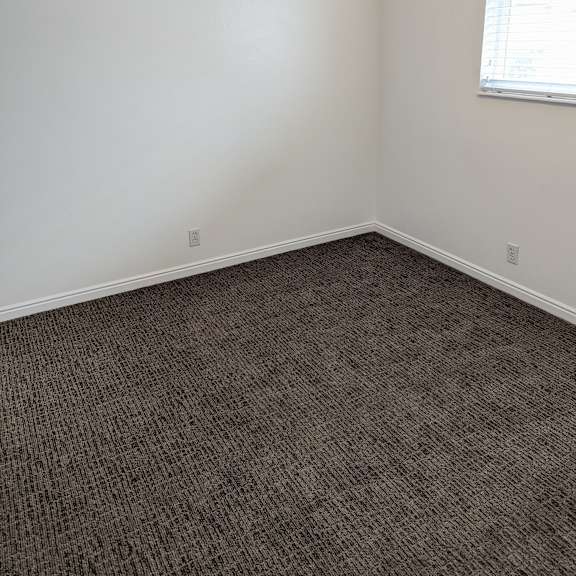 a room with a carpeted floor and a window with blinds.