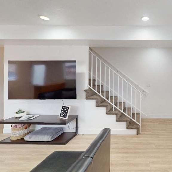 a living room with a piano and a staircase.