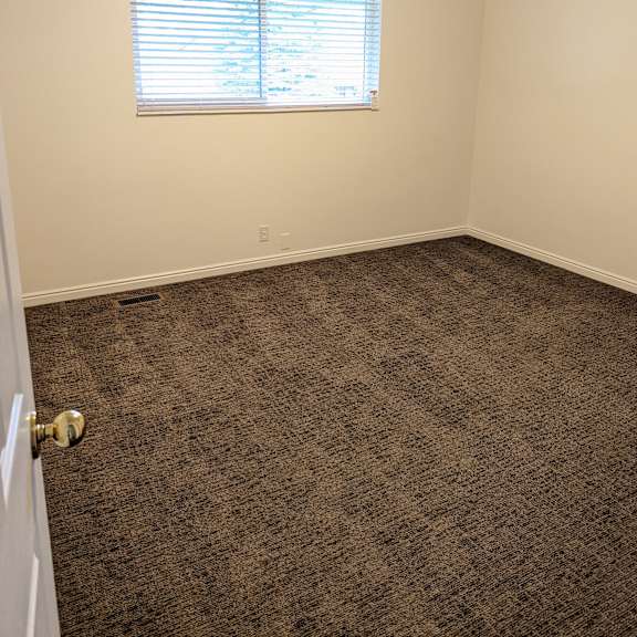 a room with a carpeted floor and a window with blinds.