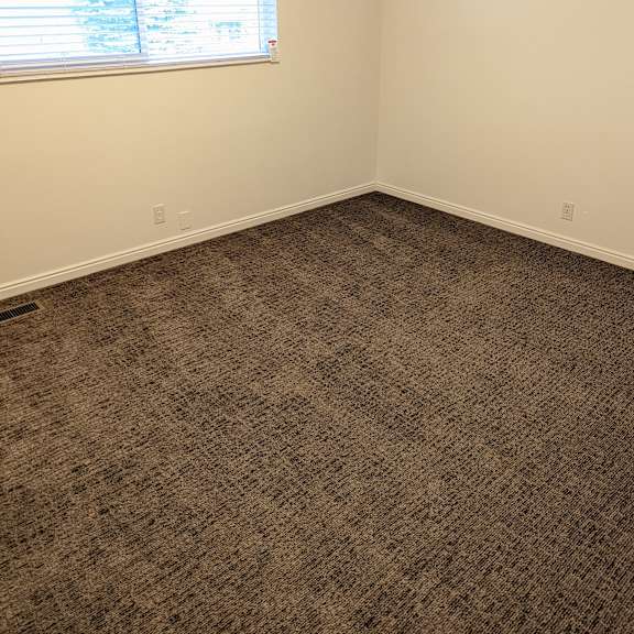 a room with a carpeted floor and a window with blinds.