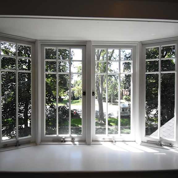 a sunny day with a view of trees through a set of white windows.