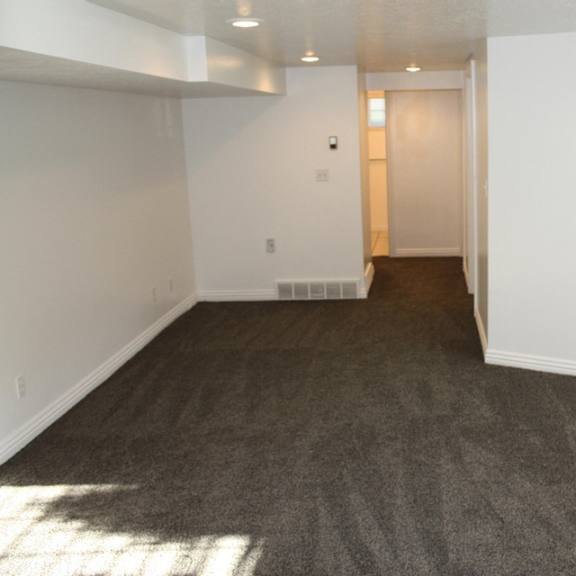 a room with a carpeted floor and a door in the distance.