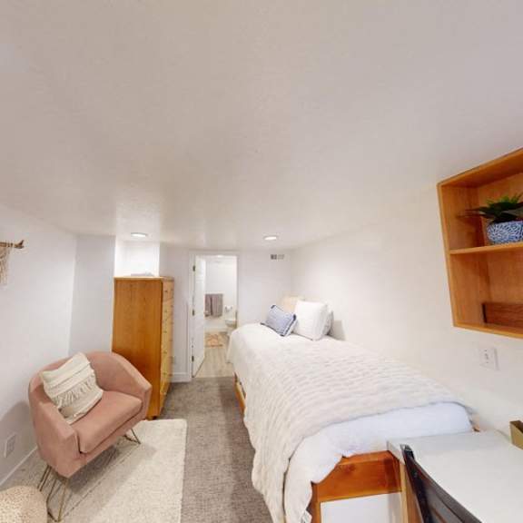 a bedroom with a bed, chair, and shelf.