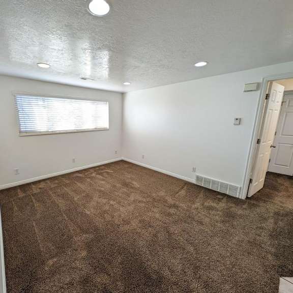 a room with a carpeted floor and a window with blinds.
