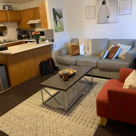 a living room with a grey couch and a red chair.