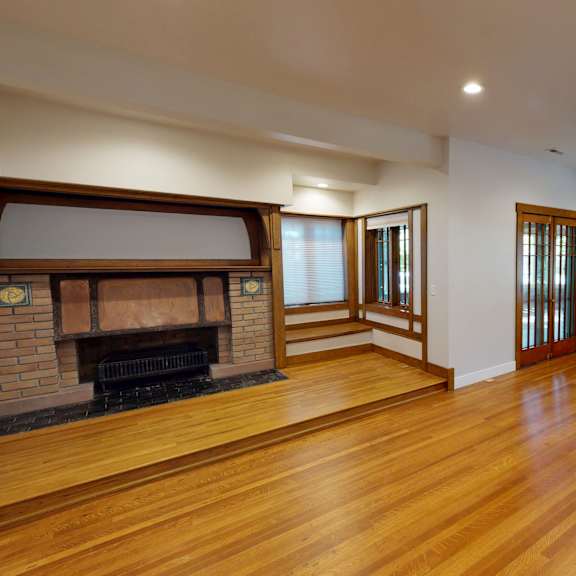a large empty room with a fireplace and wooden floors.