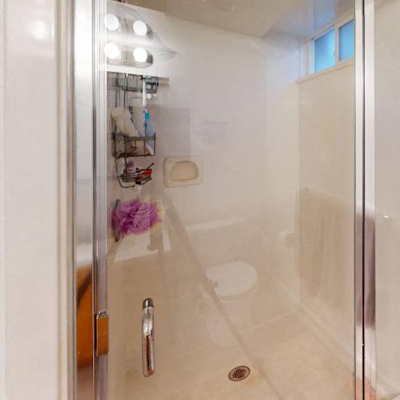a bathroom with a glass shower door and a towel hanging on the wall.