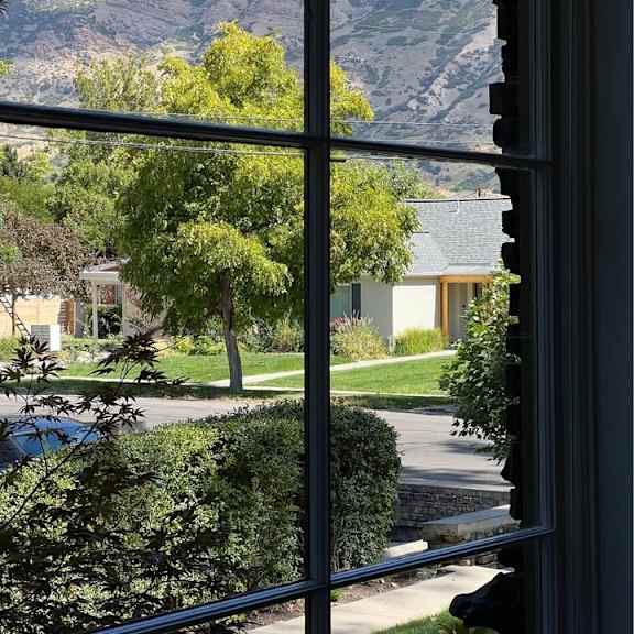 a house is seen through a window with a mountain in the background.