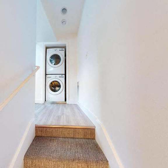 a stairway with a white wall and a wood handrail.