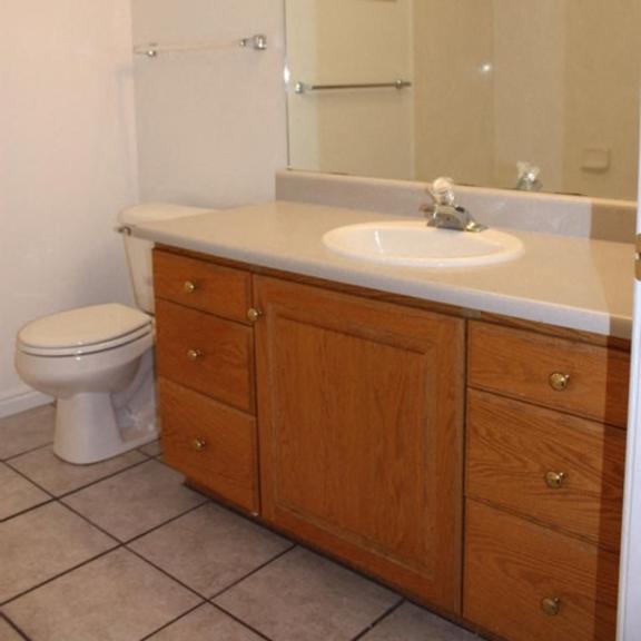 a bathroom with a toilet, sink, and mirror.