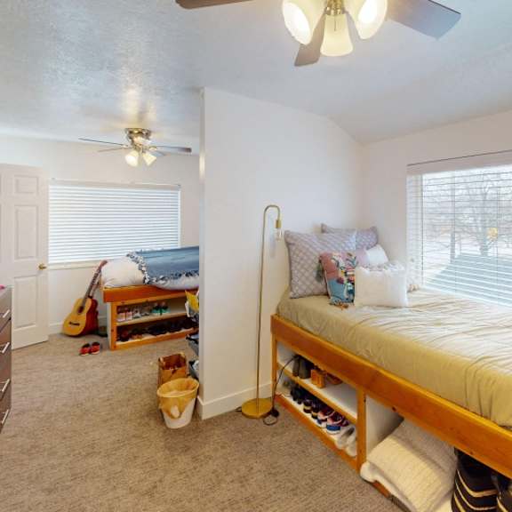 a bedroom with a bed, desk, and guitar.