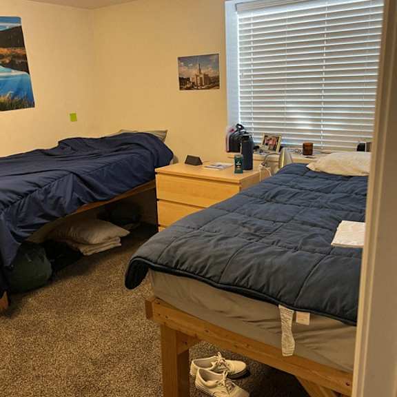 a bedroom with two beds, one of which is made up with a blue comforter.